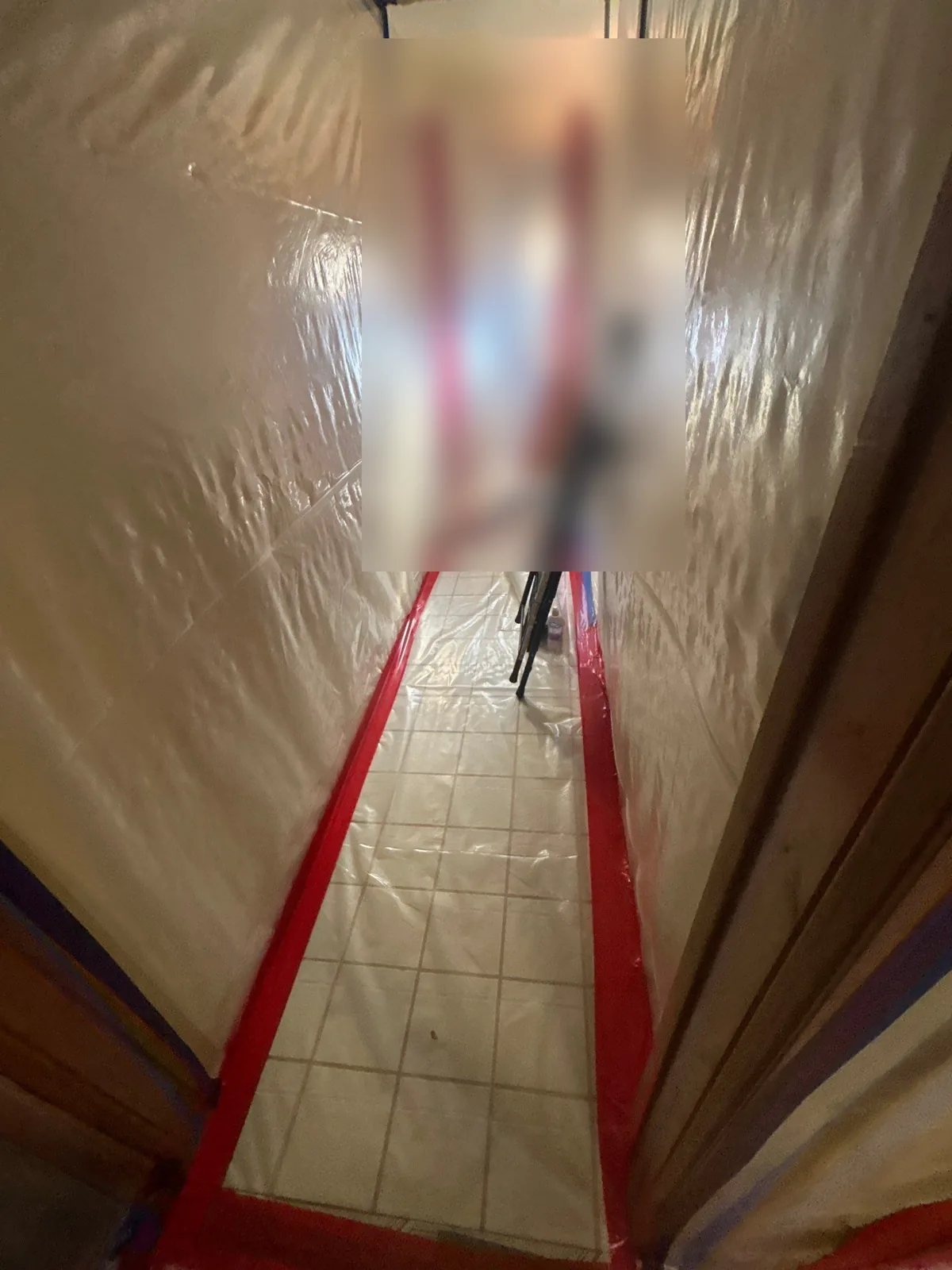 Plastic sheeting containment walls and taped floor protection sealing off a work area for mold remediation
